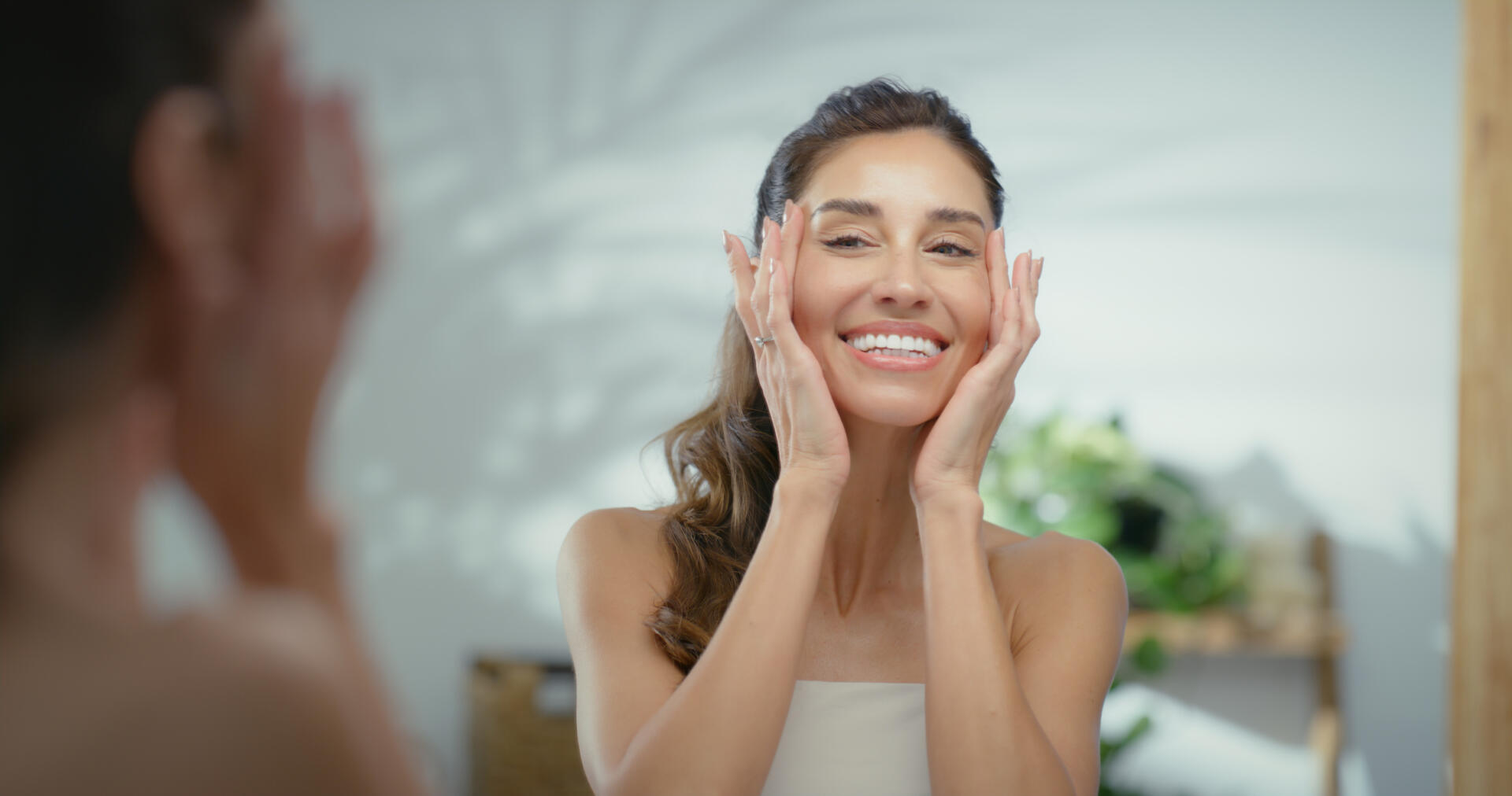 Skincare, beauty and woman by mirror in bathroom for natural, moisturizing or hydration routine. Happy, reflection, and female person with cosmetic facial treatment for dermatology in apartment.