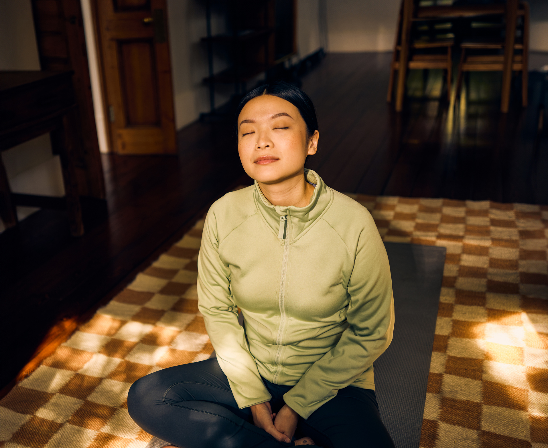 Young woman meditating in living room to reduce stress