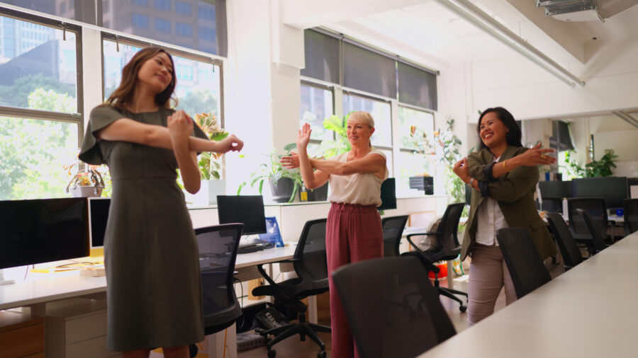 Better Support, Better Posture: The Link Between Bras and Back Health 2 Professional Businesswomen Stretching During Break in a Green Office